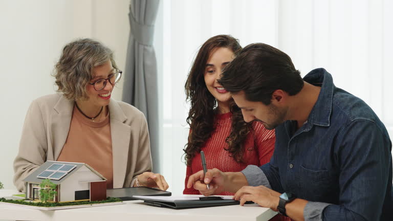 Happy couple signing home closing documents with a real estate agent