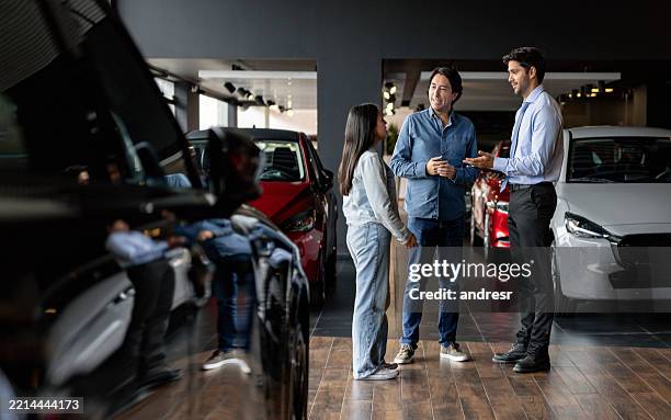 father and daughter buying a car at the dealership and talking to the salesman - buying a car stock pictures, royalty-free photos & images