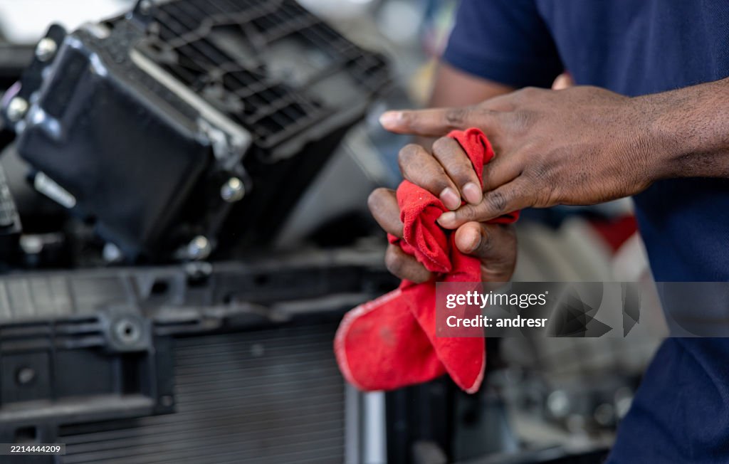 Close-up on a mechanic cleaning his hand with a cloth at a garage