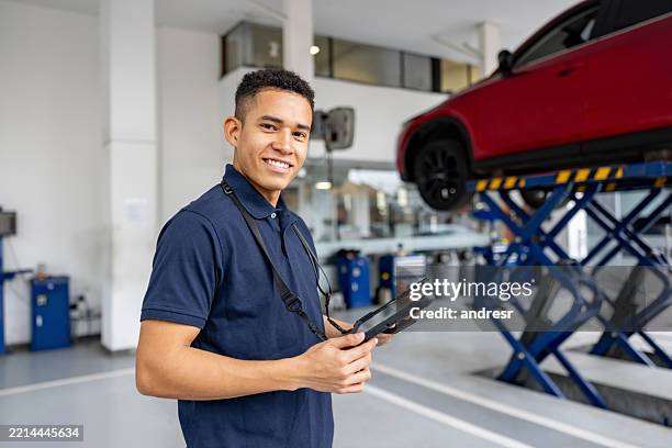 mechaniker, der in einer autowerkstatt arbeitet und ein digitales tablet in der hand hält - wartungsarbeiter stock-fotos und bilder