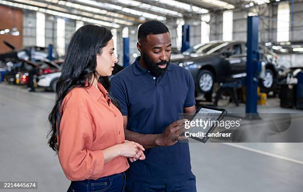 mécanicien montrant à une femme le diagnostic de sa voiture à l’aide d’une tablette - mécanicien automobile photos et images de collection
