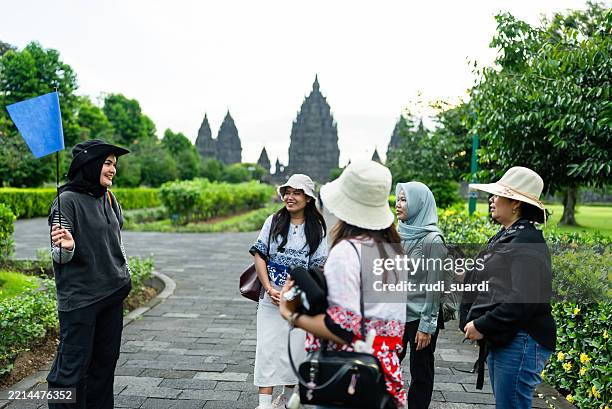 muslim tour guide showing and explaining about prambanan temple to tourist group - indian tour guide stock pictures, royalty-free photos & images