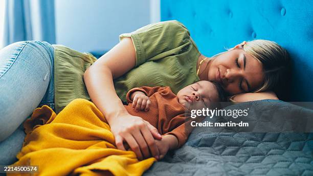 madre e bambino che riposano insieme su un letto accogliente a casa - mezzogiorno foto e immagini stock