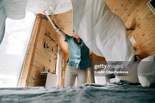 woman making bed in cozy wooden tiny house - teal fabric stock pictures, royalty-free photos & images