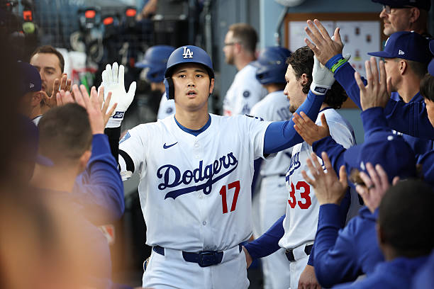 Shohei Ohtani of the Los Angeles Dodgers celebrates with teammates in the dugout after hitting a solo home run in the first inning during the game...