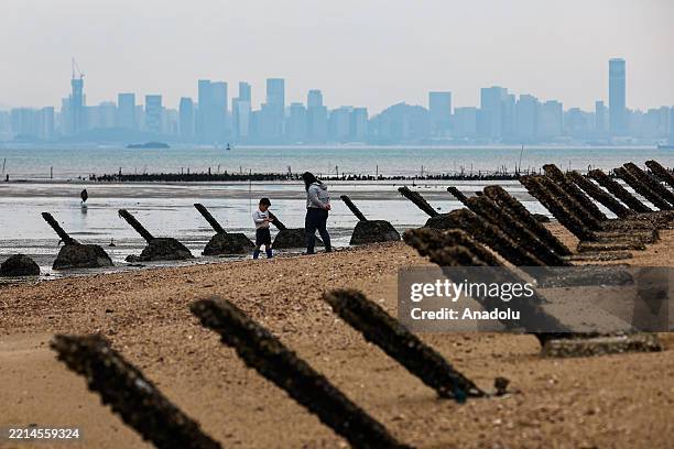 Tourists enjoy their time near the anti-landing spikes at a beach where the Chinese city of Xiamen is visible from afar, in Kinmen, Taiwan, on May...