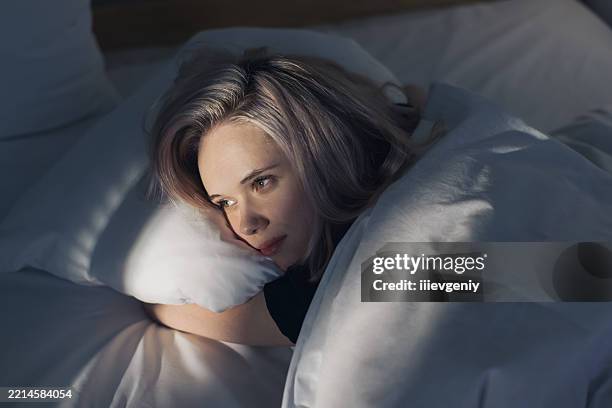 young woman on bed - restlessness stock pictures, royalty-free photos & images