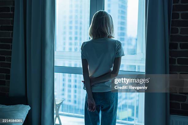young woman standing near window - suicide imagens e fotografias de stock