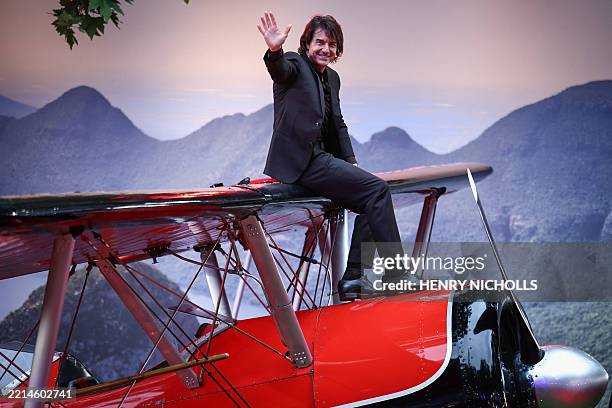 Actor Tom Cruise waves to the audience as he sits on a plane on the red carpet upon arrival for the Global Premiere of "Mission: Impossible - The...
