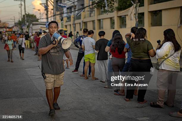 Filipinos queue to cast their votes for the midterm elections at a school converted into a polling precinct on May 12, 2025 in Manila, Philippines....