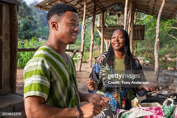 mature woman and young man preparing food for elephants while visiting sanctuary in thailand - jamaicaanse etniciteit stockfoto's en -beelden