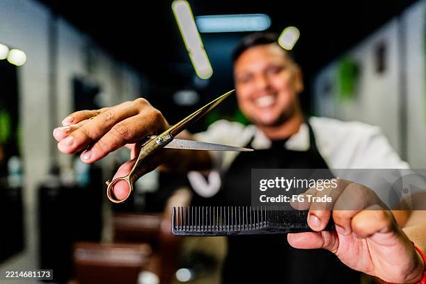 la mano del barbiere che tiene una forbice per tagliare i capelli e un pettine al barbiere - forbici per parrucchieri foto e immagini stock