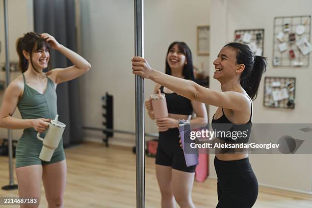 fit ladies chatting casually while drinking water post pole workout - pole dance stock pictures, royalty-free photos & images