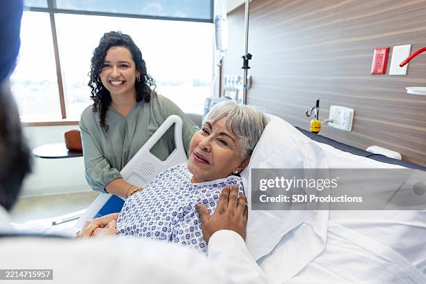 un médecin réconforte une personne âgée avec sa famille présente dans la chambre d’hôpital - contact avec les patients photos et images de collection