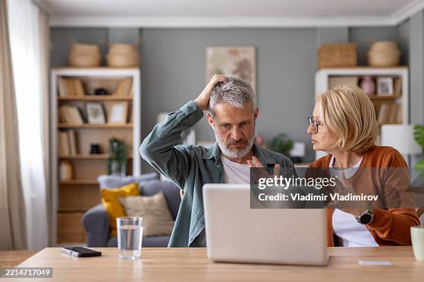 a couple navigates technology challenges together at home - verward stockfoto's en -beelden
