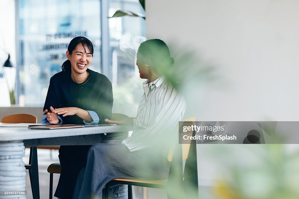 カジュアルなチームミーティングで笑い合う2人の幸せな同僚