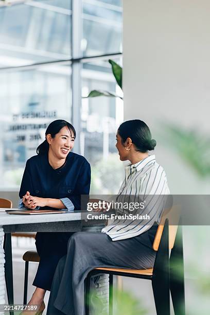 two professionals enjoying a friendly conversation in a modern office space - happy colleagues doing team building activity imagens e fotografias de stock