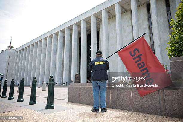 Man holds a flag that reads "Shame" outside the Library of Congress on May 12, 2025 in Washington, DC. On May 8th, President Donald Trump fired Carla...