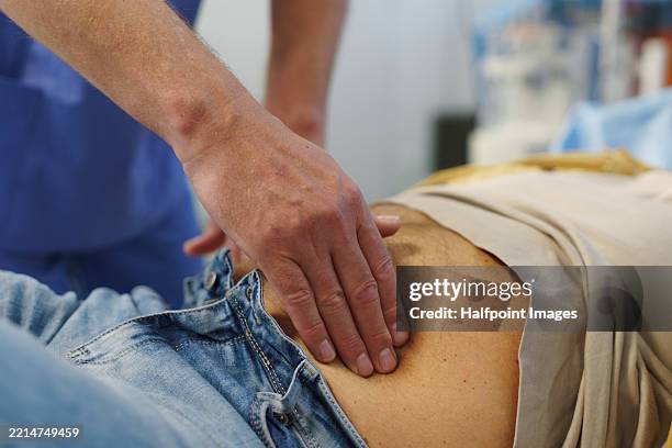 doctor performing abdominal palpation on senior patient in emergency room. - darmen stockfoto's en -beelden