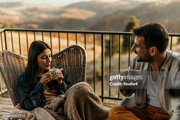 couple enjoying hot drinks on balcony with scenic view - coffee drop stock pictures, royalty-free photos & images