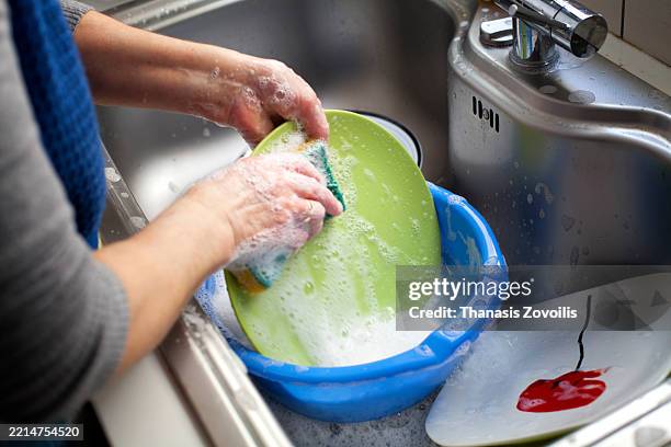 washing dishes in soapy water using a sponge at the sink - scrubbing stock pictures, royalty-free photos & images
