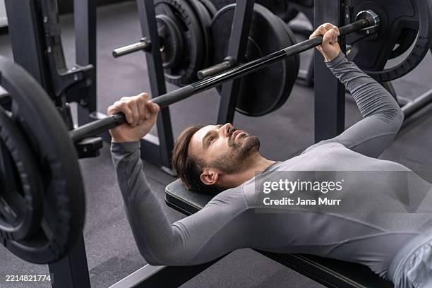 man executing a bench press in a gym setting - weight bench stock pictures, royalty-free photos & images