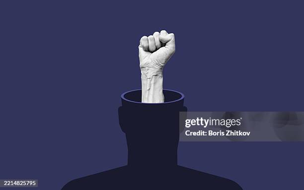power of mind. raised fist emerging from human head silhouette - faust stock-fotos und bilder