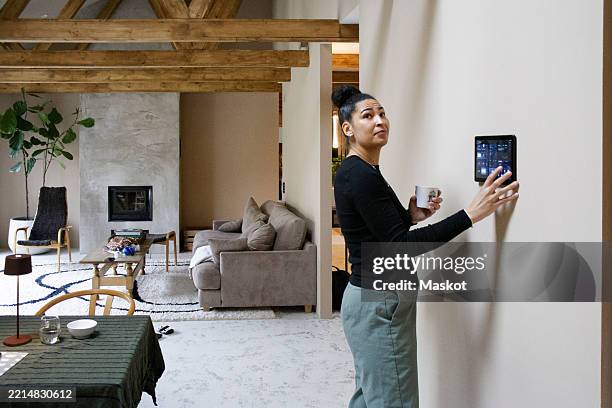 side view of woman adjusting room temperature through app on digital tablet - domotica foto e immagini stock