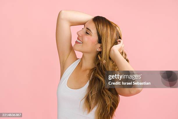 gorgeous hispanic woman with long hair posing on pink background - haarkleur stockfoto's en -beelden