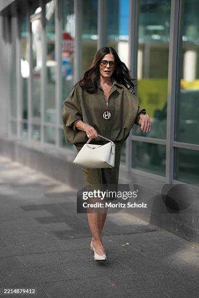 Angelika Hanel is seen wearing a faux suede bomber jacket with a lapel collar, long batwing sleeves and shoulder tabs in khaki from Zara, a matching...