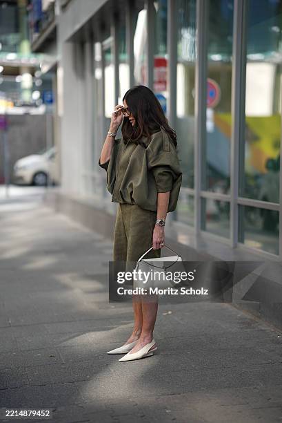 Angelika Hanel is seen wearing a faux suede bomber jacket with a lapel collar, long batwing sleeves and shoulder tabs in khaki from Zara, a matching...