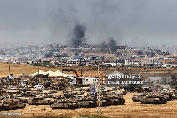 This picture taken from a position in southern Israel on the border with the Gaza Strip shows Israeli tanks and bulldozers deployed as smoke billows...