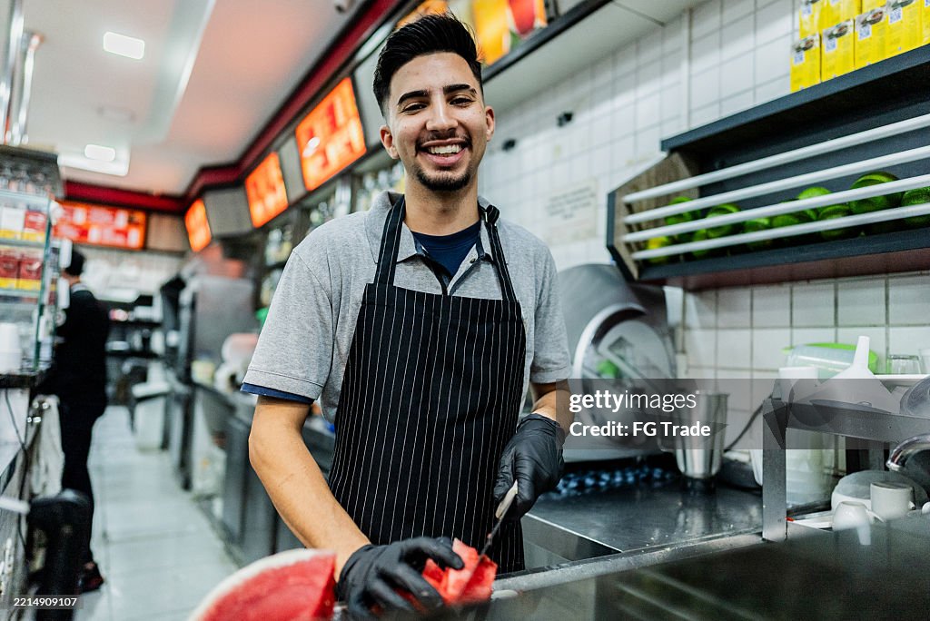 Porträt eines jungen Mannes, der Wassermelone im Restaurant schneidet