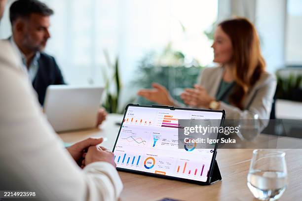 das business-team analysiert finanzdaten auf einem digitalen tablet während eines meetings - reporting stock-fotos und bilder