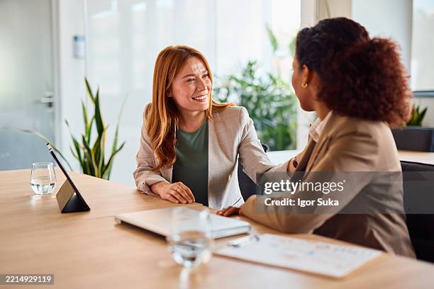 donne d'affari che confortano il collega durante la riunione nella sala riunioni dell'ufficio - empatia foto e immagini stock