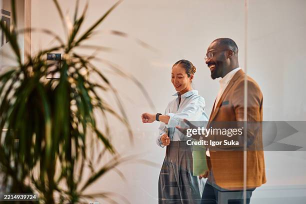 businesspeople checking time walking in office corridor during break time - checking the time stock pictures, royalty-free photos & images