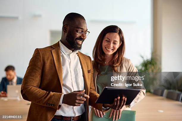 smiling business people using digital tablet in modern office - leader stock pictures, royalty-free photos & images