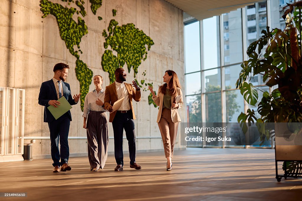 Geschäftsleute, die in modernem Büro mit Mooswanddekoration spazieren gehen und reden