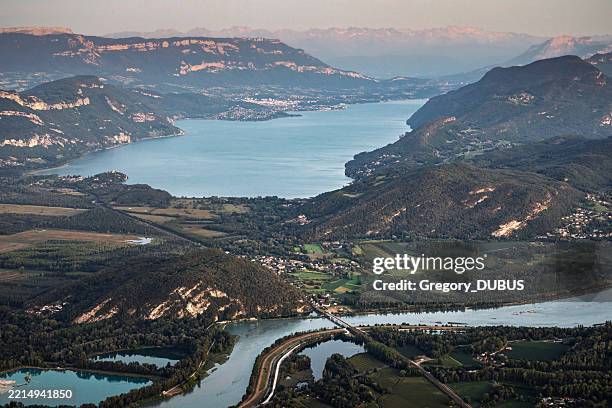 aerial view on french lake bourget with rhone river in foreground and aix-les-bains city in the background at dusk - river rhone stock pictures, royalty-free photos & images