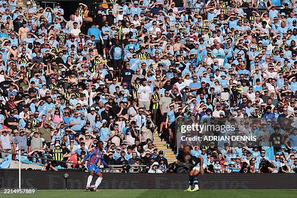 Manchester City fans shield their eyes from the sun as they watch the action during the English FA Cup final football match between Crystal Palace...