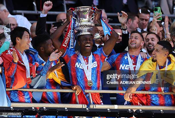 Crystal Palace's English defender Marc Guehi lifts the trophy as Crystal Palace players celebrate after the English FA Cup final football match...