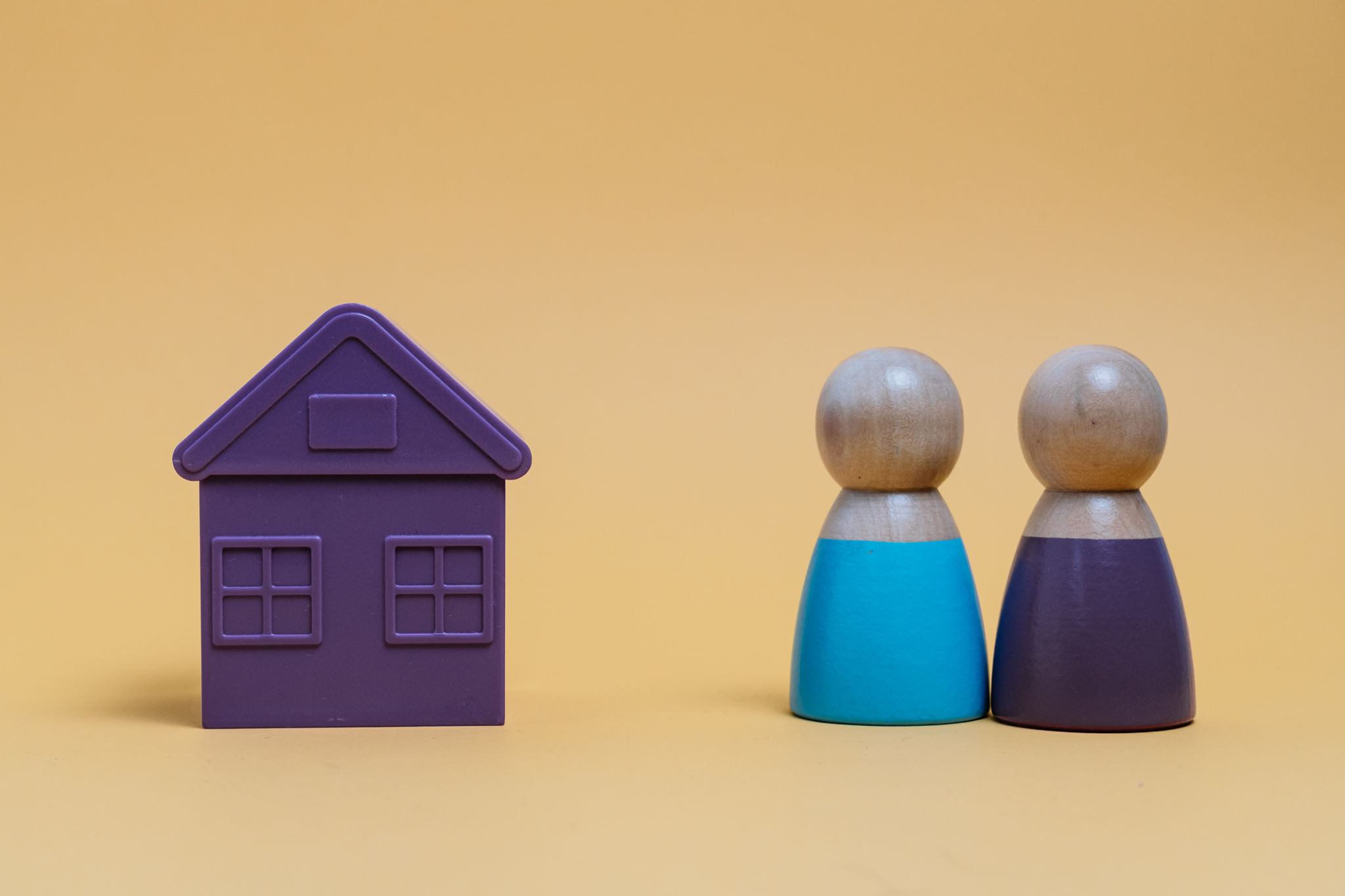 Couple looking at miniature house representing housing market Couple looking at miniature house representing housing market