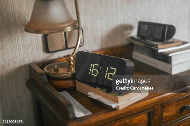 digital alarm clock on a bedside table in a cozy bedroom. symbol of routine, morning time, and daily life in a modern home interior. - digitaluhr stock-fotos und bilder