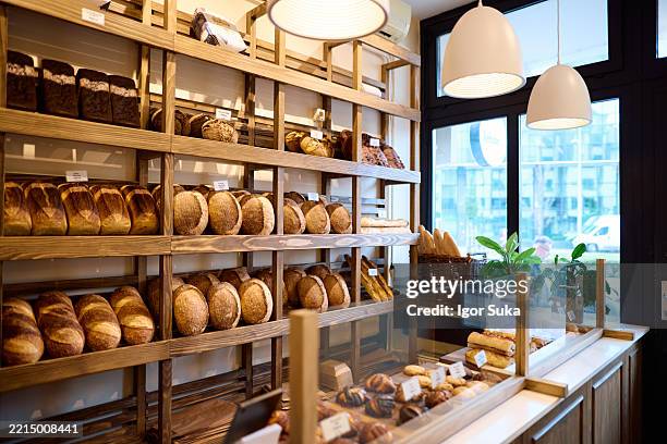pan recién horneado exhibido en estantes de madera en una panadería - panadería fotografías e imágenes de stock