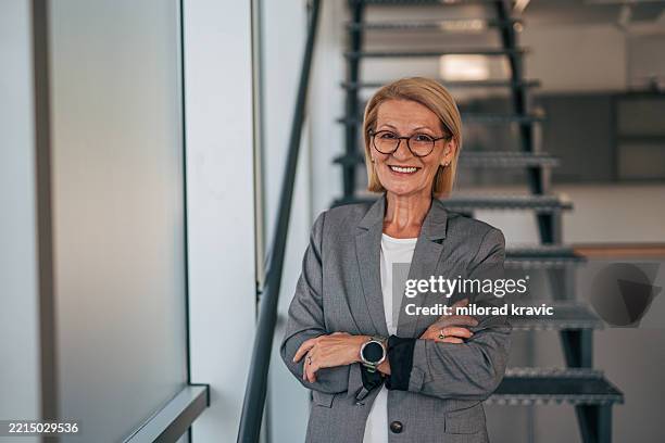 exitosa mujer de negocios senior sonriendo con confianza en una oficina moderna - director ejecutivo fotografías e imágenes de stock