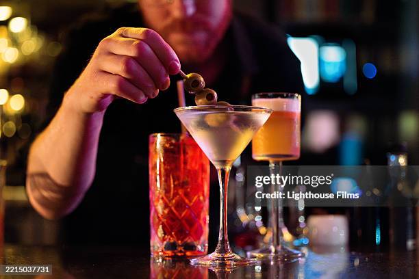 a bartender puts olives into a martini and a trendy bar - martini stock pictures, royalty-free photos & images