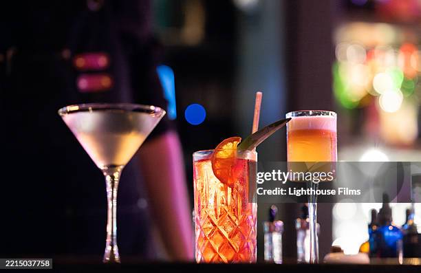 three vibrant cocktails sit in a dark, trendy bar - ethanol stock pictures, royalty-free photos & images
