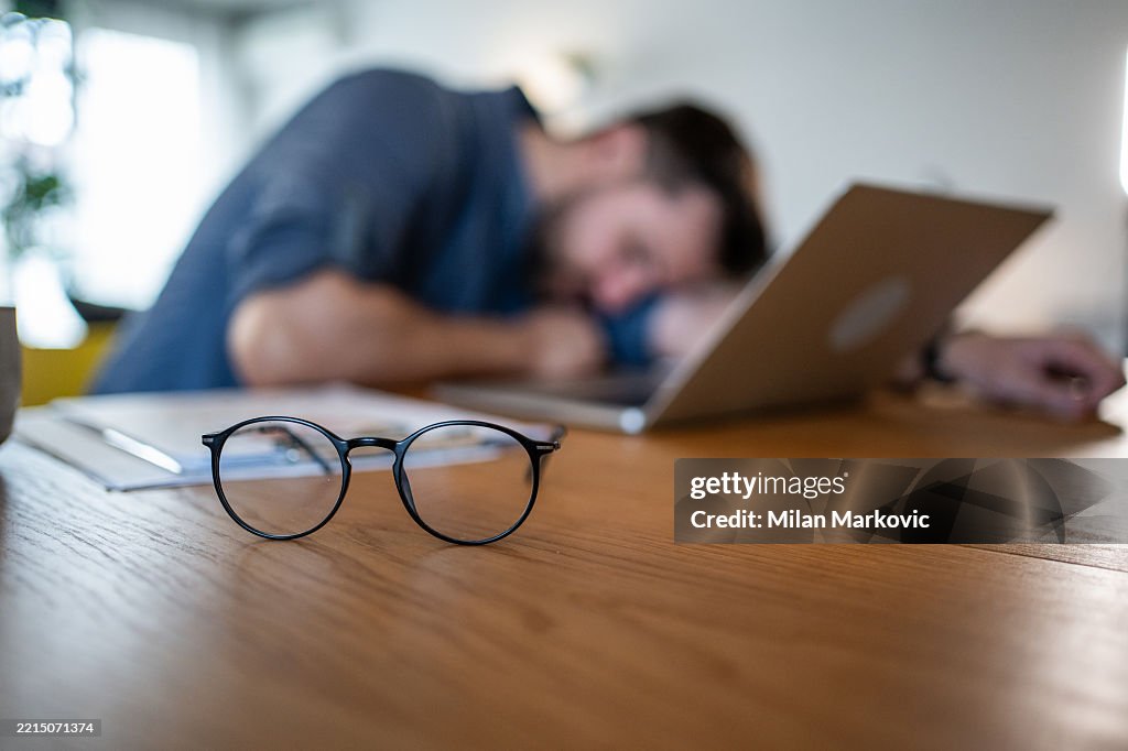Exhausted freelancer sleeping at his desk after working late