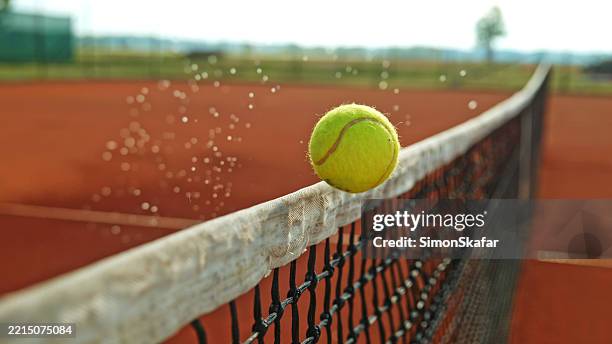 tennis ball hitting the net during a match on a clay court - tennis stock pictures, royalty-free photos & images
