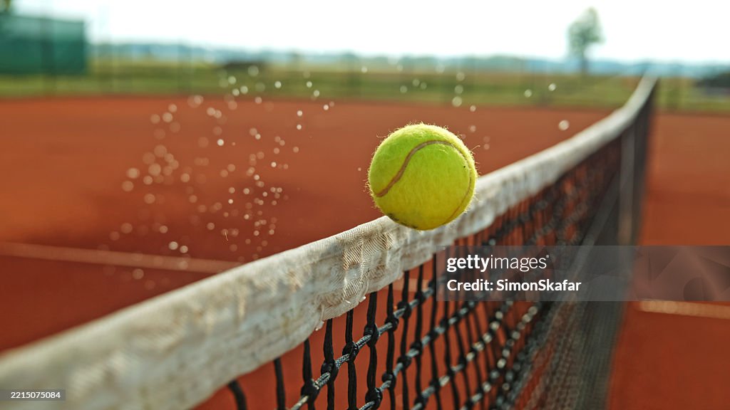 Tennis Ball Hitting the Net During a Match on a Clay Court
